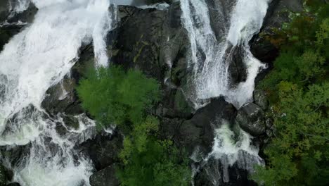 Roaring-waterfall-filmed-from-above-in-the-rough-nature-of-Norway-with-a-road-flying-over-it