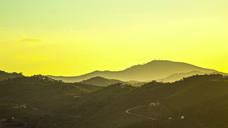 Golden-sunrise-over-hilly-landscape,-silhouette-of-mountains,-serene-and-calm-early-morning