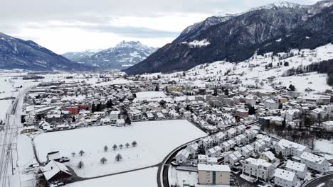 Aerial-wide-shot-showing-snowcapped-landscape-and-snow-covered-houses-in-swiss-village-named-Reichenburg