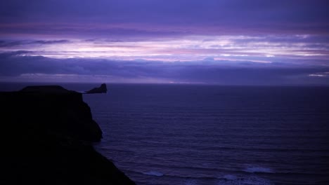 Man-walks-near-the-sea-with-stunning-purple-sunset