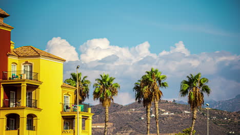 Sunny-day-view-of-palm-trees-and-colorful-buildings-with-mountains-in-the-background