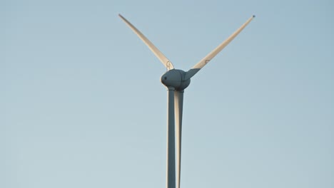 Close-up-of-a-wind-turbine-blade-rotation-in-a-clear-blue-sky,-emphasizing-clean-energy-production