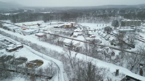 Aerial-pan-across-snow-covered-filtration-plant-and-business-distrct-next-to-railroad-tracks