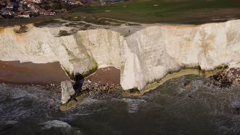 Drone-shot-of-white-cliffs-with-a-lone-man-at-the-edge