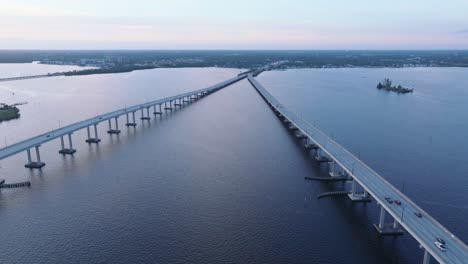 Aerial-forward-flight-over-river-between-busy-bridges-during-blue-hour-in-Fort-Myers,-Florida---Establishing-drone-shot