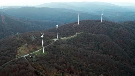 Aerial-view-of-wind-turbines-on-a-forested-mountain-ridge,-showcasing-sustainable-energy-in-a-natural-setting
