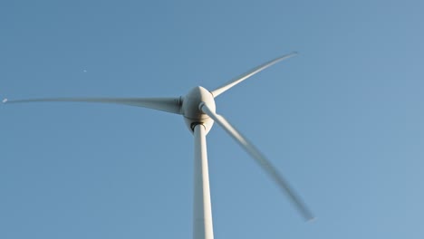 Wind-turbine-rotating-against-a-clear-blue-sky,-symbolizing-sustainable-energy-and-technology