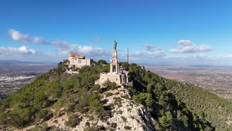 Aerial-orbiting-flight-around-famous-Sant-Salvador-Statue-on-top-of-mountain-during-sunny-day-on-Mallorca-Island