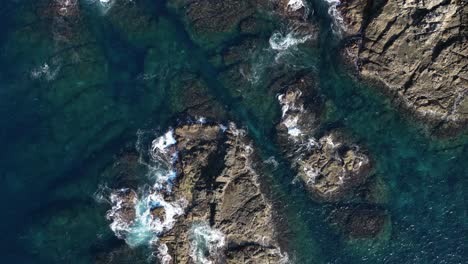 Drohnenansicht-Von-Oben-Nach-Unten-Auf-Wellen,-Die-Auf-Kleinen-Felsigen-Inseln-Zerquetschen