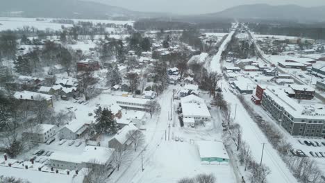Aerial-dolly-above-snow-packed-roads-and-buildings-next-to-white-railroad-tracks