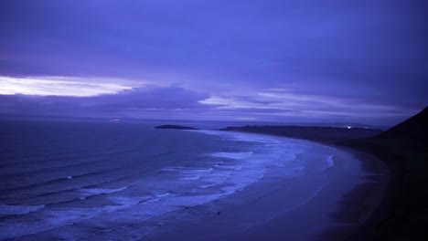 Purple-sky-overlooking-expansive-beach-in-Wales,-Rhossili