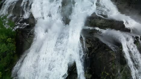 Roaring-waterfall-filmed-from-above-in-the-rough-nature-of-Norway-with-a-road-flying-over-it