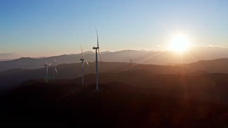 Sonnenuntergang-Beleuchtet-Windkraftanlagen-Auf-Sanften-Hügeln,-Aufgenommen-Aus-Der-Luftperspektive-Mit-Schwerpunkt-Auf-Erneuerbaren-Energien