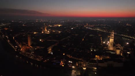 Luftaufnahme-Einer-Gegen-Den-Uhrzeigersinn-Rotierenden-Drohne,-Des-Stadtzentrums-Von-Verona-Bei-Nacht-Mit-Sonnenuntergang