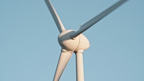 Close-up-of-wind-turbine-hub-and-blades-against-a-clear-blue-sky,-highlighting-clean-energy
