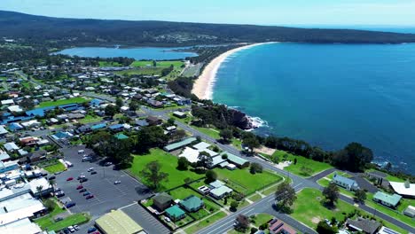 Drone-aerial-over-residential-housing-and-commercial-shops-holiday-town-street-roads-Aslings-Beach-Twofold-Bay-Eden-South-Coast-Australia