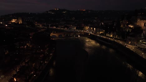 Aerial-Forward-lateral-Reveal-Drone-Shot,-of-Ponte-Pietra-Bridge-in-Verona-at-Night