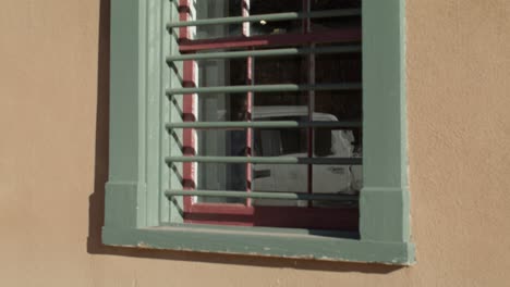 Grün-Gerahmtes-Fenster-An-Einem-Haus-Im-Adobe-Stil-In-Santa-Fe,-New-Mexico,-Mit-Nach-Unten-Kippendem-Video