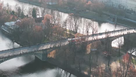 Aerial-follow-of-city-public-transportation-tram-cross-river-on-bridge