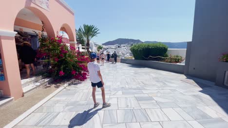 People-Shopping-Along-White-Pathway-|-Oia-Santorini-Greece-Greek-Island-in-Aegean-Sea,-Travel-Tourist-Vacation-Immersive-Moving-Walk-Along-Crowds-Shopping-in-White-Marble-Cliffside-and-City,-Europe,4K