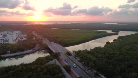 Sunset-aerial-drone-shot-over-the-Punta-Nizuc-bridge-over-the-Nichupte-lagoon-in-Cancun-Mexico-surrounded-by-rivers-and-marshland