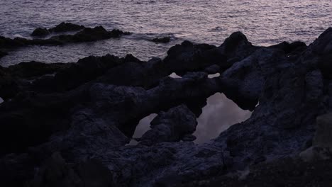 Night-waves-dance-on-Tenerife's-volcanic-rocks,-dramatic-and-serene-seascape