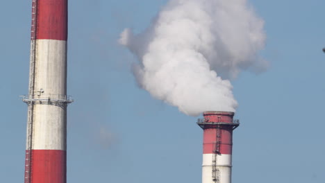 Zwei-Industrielle-Schornsteine-Setzen-Dampf-Vor-Blauem-Himmel-Frei-Und-Symbolisieren-Energieerzeugung-Und-Umweltauswirkungen
