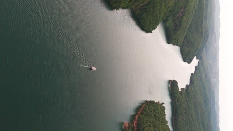 Vertical-aerial-view-of-boat-cruise-through-Albanian-mountain-forest-valley