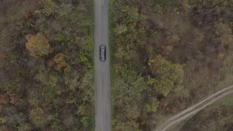 Retreating-follow-through-drone-shot-of-a-moving-vehicle-on-a-road-located-at-the-foot-of-the-Balkan-Mountains-in-Bulgaria