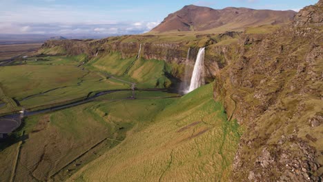 Aerial-view-of-Seljalandsfoss-waterfall-in-Iceland,-green-landscape-with-cascading-water-and-clear-skies