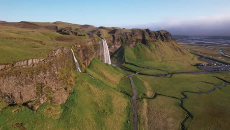 Aerial-view-of-majestic-waterfalls-in-green-Icelandic-landscape-during-sunny-day