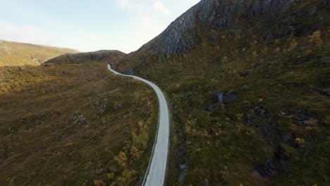 Drone-footage-diving-down-from-above-and-following-a-road-during-autumn-in-northern-Norway