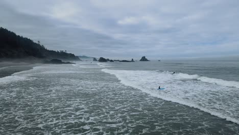 Aerial-view-flying-over-surfers-in-the-cold-water-on-Indian-Beach-in-Oregon