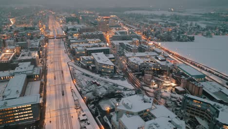 Verschneite-Städtische-Dämmerung:-Luftaufnahme-Des-Verkehrs-Auf-Den-Straßen-Der-Stadt,-Beleuchtet-Von-Abendlichtern