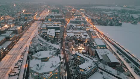 Verschneite-Städtische-Dämmerung:-Luftaufnahme-Des-Verkehrs-Auf-Den-Straßen-Der-Stadt,-Beleuchtet-Von-Abendlichtern