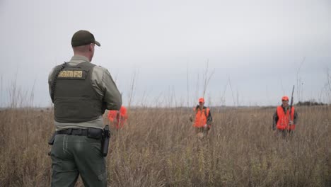 Conservation-officer-greeting-pheasant-hunters-in-a-field