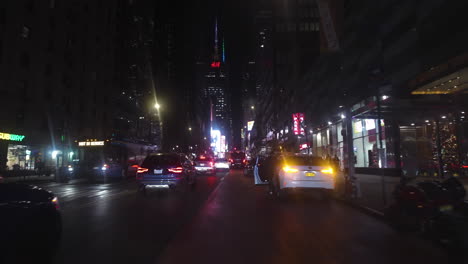 POV-shot-driving-a-moped-in-middle-of-cars-on-the-illuminated-streets-of-New-York,-USA