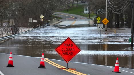 Road-closed-ahead-sign-with-flooded-bridge-after-heavy-rainfall-in-USA