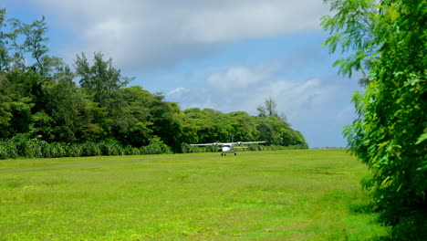 Wide-shot-of-a-small-charter-plane-landing-on-green-grass-runway