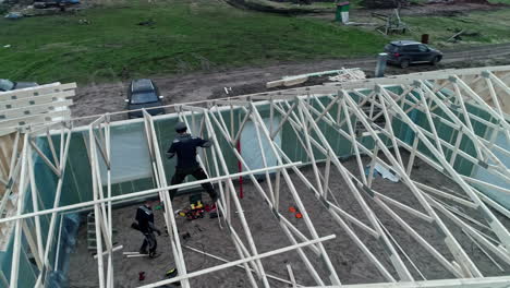 Luftdrohne-über-Einem-Holzdach,-Das-Von-Kaukasischen-Arbeitern-Mit-Balken-Gebaut-Wird