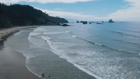 Timelapse-De-Surfistas-Y-Olas-Bajo-Un-Cielo-Azul-En-Indian-Beach,-Oregon