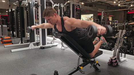 Caucasian-Blond-Man-Bodybuilder-Training-Rear-Delts-Muscular-Doing-Dumbbell-Shoulder-Fly-or-Raises-Exercise-Leaning-on-Angled-Bench