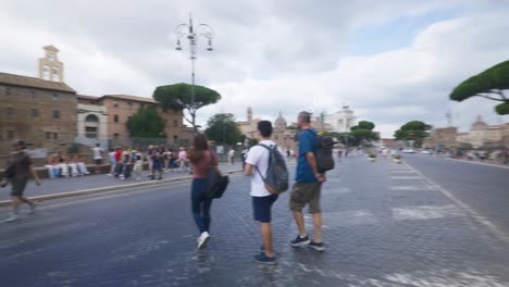 Rome-Immersive-POV:-Moving-In-Busy-Streets-to-Chiesa-Santi-Luca-e-Martina,-Italy,-Europe,-Walking,-Shaky,-4K-|-Crossing-Crowd-Street-With-Colosseum-In-Distance