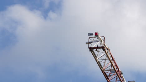 A-tall-construction-crane-towering-against-a-clear-blue-sky,-with-red-and-white-colors-on-the-machinery