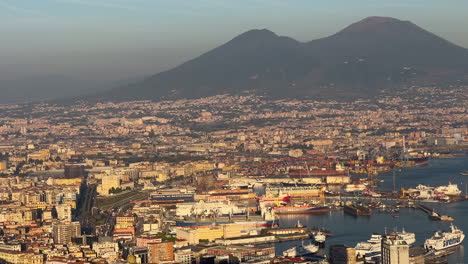 The-bustling-port-of-Naples-with-ships-docked-in-the-harbor,-overlooked-by-the-towering-Mount-Vesuvius-in-the-golden-light-of-dusk