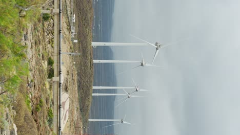 Vertical-view-of-spinning-wind-turbines-on-cloudy-moody-day