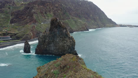 Ribeira-da-Janela-Porto-Moniz-Seixal-Madeira-drone-shot-fly-back-rocks-with-sea-ocean-waves-on-a-cloudy-day