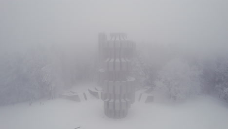 Aerial-view-of-Monument-to-the-Revolution-in-Kozara,-Bosnia-and-Herzegovina-in-the-foggy-winter