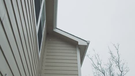 Schneeflocken-Fallen-Neben-Der-Holzfassade-Eines-Amerikanischen-Hauses,-Zeitlupe