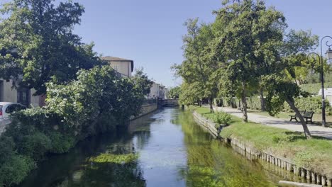 small,-wide-river-in-France-in-a-small-town-by-a-park-in-good-sunny-weather-with-small-stone-houses-and-lots-of-nature-and-a-bridge